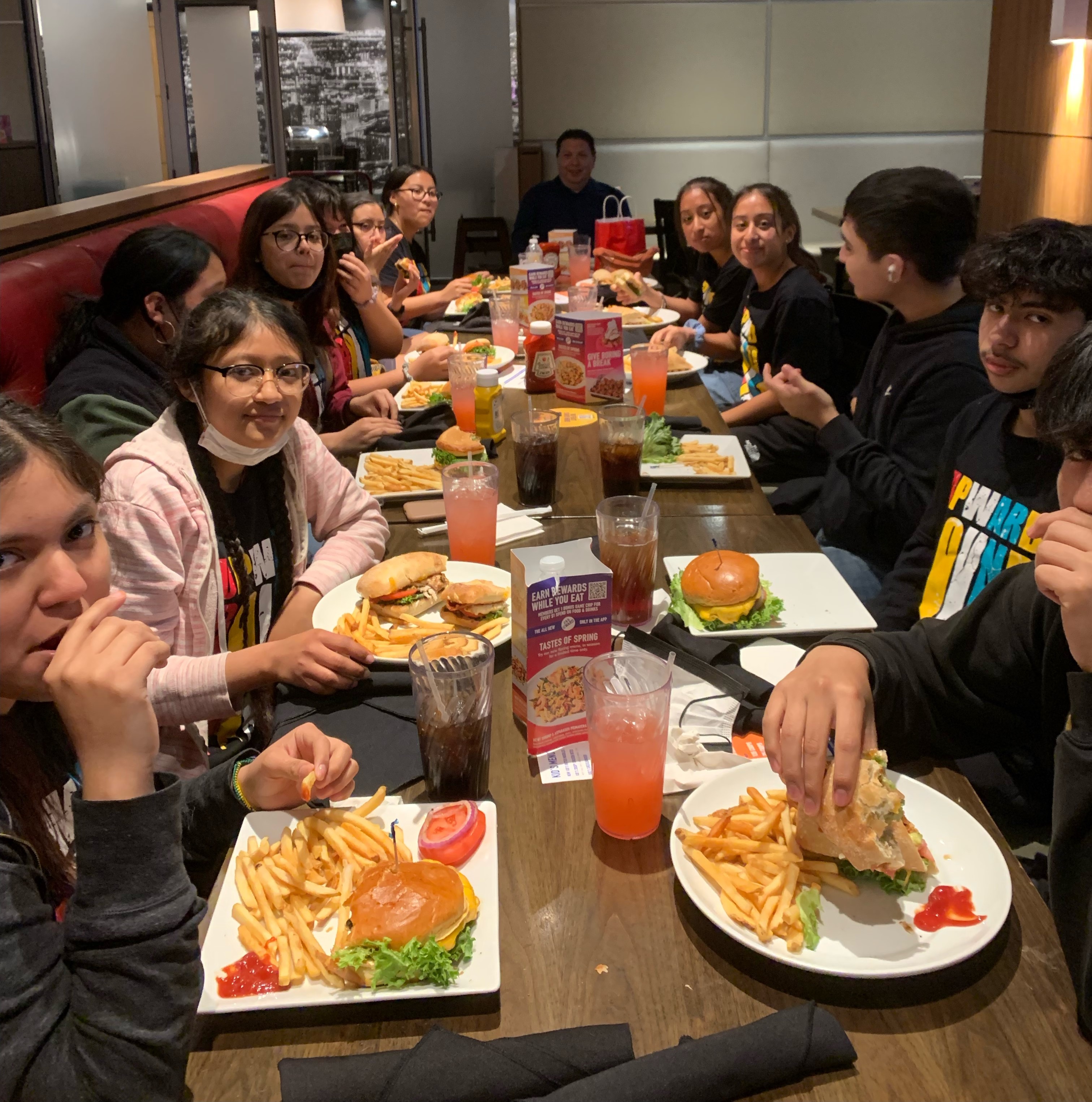 Picture of students around a large lunch table eating food.